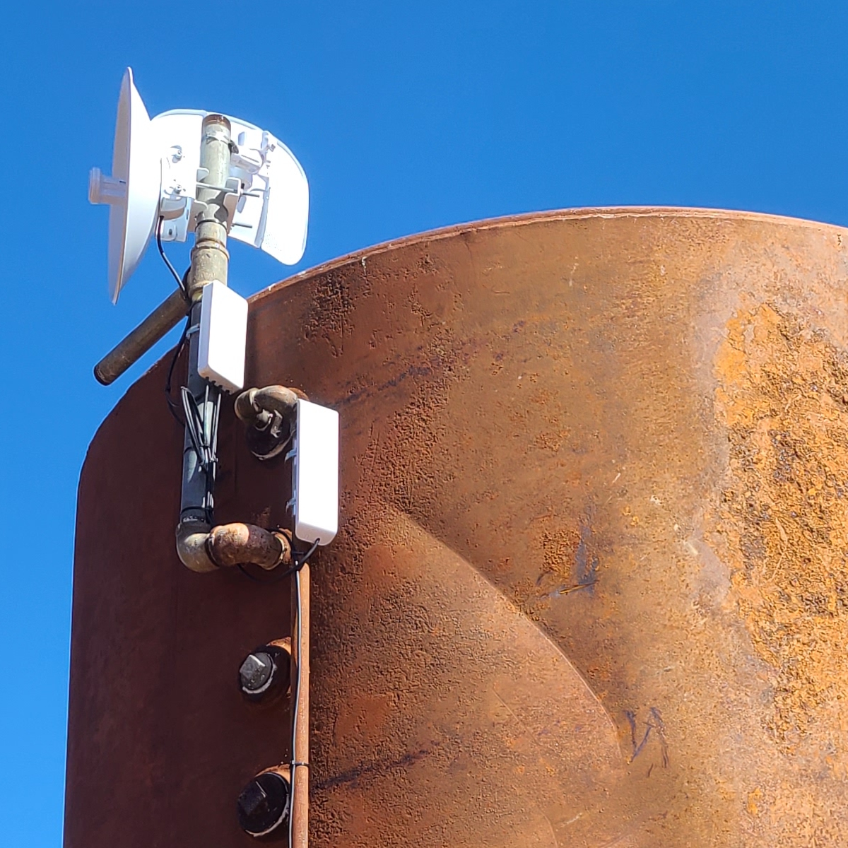 A repeater atop a water tank, consisting of a PowerBeam 5AC, LiteBeam 5AC, NanoSwitch, and NanoStation M2.